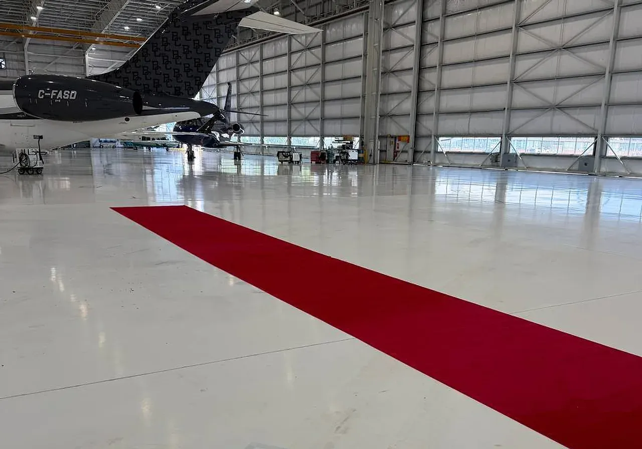 Red carpet runner laid in a diagonal across a polished aircraft hangar floor